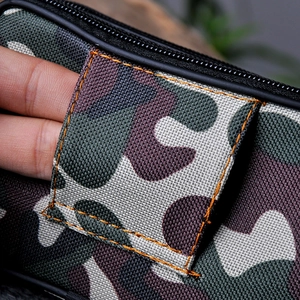 Close-up of camouflage canvas waist bag showing side pocket detail and durable fabric