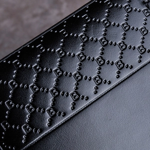 Close-up of black leather wallet with luxury monogram pattern and textured finish