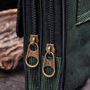Detail of green Oxford fabric waist bag with dual metal zippers and ripstop texture