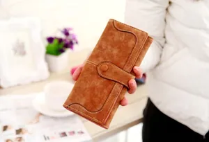 Close-up of brown matte suede long wallet with wavy flap and white contrast stitching