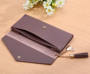 Detail view of mauve flap wallet with gold snap and heart fringe tassel pendant