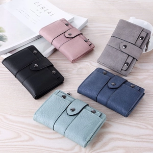 Flat lay of colorful matte faux leather tri-fold wallets with rivets on wood surface