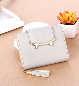 Close-up of light gray short folding wallet with gold cat ear clasp and leather tassel