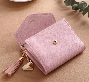 Detailed close-up of pink litchi grain wallet with gold heart tassel and snap closure