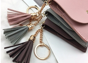 Close-up of mini faux leather coin purses with long tassels and gold metal keychains