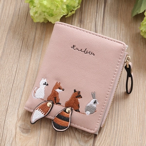 Pink PU leather short wallet with cute animal embroidery and metal zipper on wood desk