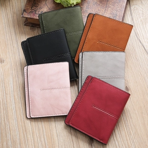 Close-up of minimalist bi-fold wallets in six colors on a wooden background with leather texture