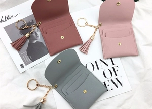 Detailed view of card wallets with tassels in bean paste, pale pink, and grey blue colors