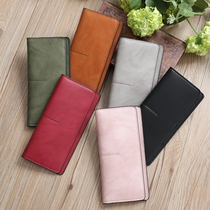 Flat lay of minimalist slim long wallets in diverse matte colors on a wooden background