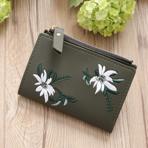 Close-up of olive green mini wallet with floral embroidery and golden zipper detail
