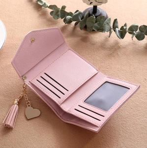 Detail view of pink trifold wallet interior with card slots and tassel pendant charm
