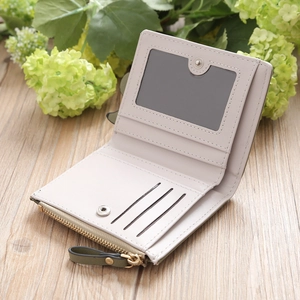 Detail of a women's mini bi-fold wallet featuring olive green trim and gold hardware