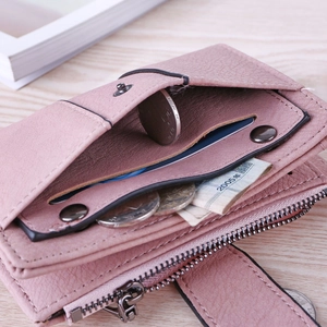 Macro view of women's matte pink tri-fold wallet with card slots and metal snap closure