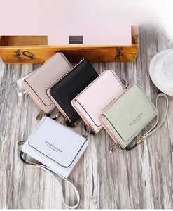 Flat lay of colorful tri-fold faux leather wallets with wristlets on wooden surface