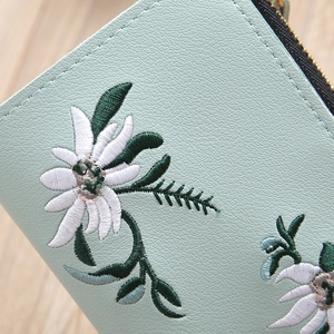 Detail of mint green lychee grain leather wallet with white flower embroidery and zipper