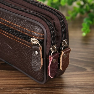 Close-up of brown leather waist bag featuring triple zippers and orange stitching