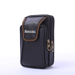 Close-up of black vertical waist bag with orange double stitching and metal brand plaque