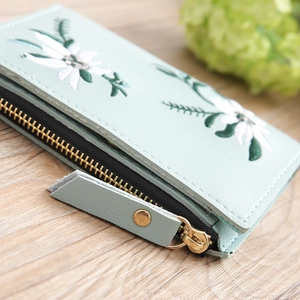 Detail of mint green PU leather wallet featuring floral embroidery and gold zipper hardware