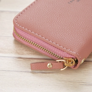 Detail of the litchi grain texture and gold metal zipper on a dusty rose handbag