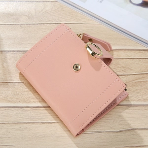 Detailed view of pink PU leather short wallet with gold ring buckle on wood surface