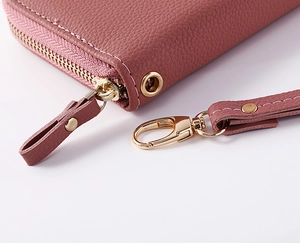 Detail of lychee pattern leather wallet in dusty rose with golden zipper and wrist strap