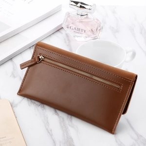 Detailed view of brown trifold long wallet with matte texture on marble desktop