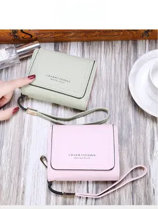 Detailed view of trifold PU leather wallets in mint green and pink with wrist straps