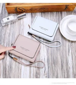Three-fold short wallets in blue and pink with a wrist strap on a wooden desk