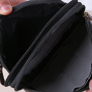 Macro view of two spacious compartments and metal zippers on a black leather waist bag