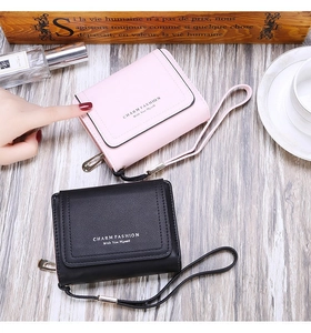 Detail of compact tri-fold wallets in pink and black featuring golden snap closure