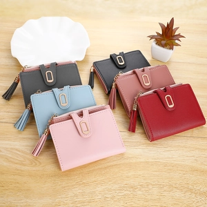 Flat lay of colorful mini women's wallets with tassel charms on a wooden surface