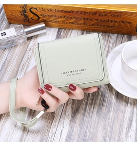 Detail of mint green tri-fold wallet with strap and embossed Charm Fashion lettering