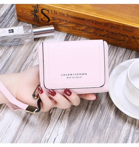 Detail of pink faux leather trifold wallet with zip and strap in elegant lifestyle setting