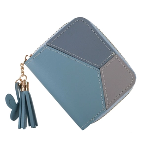 Détail du portefeuille bicolore avec surpiqûres, pompon à franges et pendentif papillon