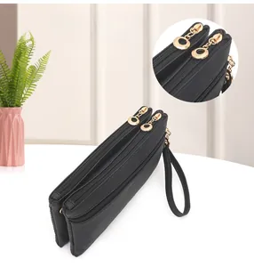 Detail of black pebbled leather double zipper wristlet with gold hardware and wrist strap
