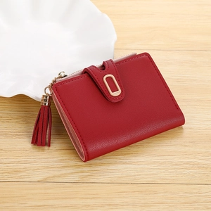 Close-up of wine red leather wallet with gold hardware and tassel detail on wood background
