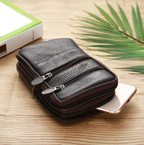 Macro view of three-zipper men's leather waist bag showing large storage on wooden surface