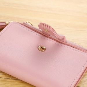 Close-up of pink short wallet showing pebbled leather texture and tassel zipper detail