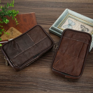 Brown leather waist bag with zipper and belt loop displayed on a wooden table