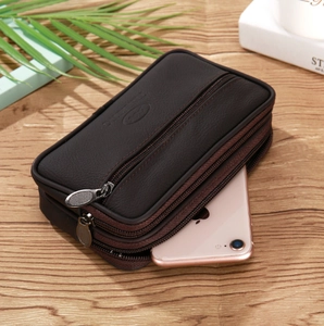 Close-up of brown leather waist bag with three zipper pockets on a wooden desk