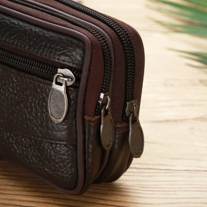 Detail view of large dark brown synthetic leather phone holster with three zipper pockets