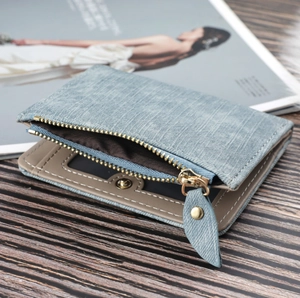 Macro detail of canvas wallet featuring a metal snap button and zipper pocket