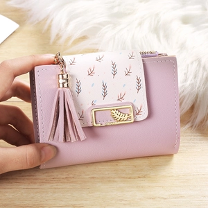 Detail of a mauve pink leather bifold wallet with leaf print and gold hardware