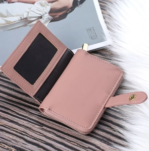 Detail of pink faux leather wallet with golden zipper, card slots and ID window