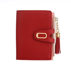 Short red foldable women's wallet with tassel charm and gold zipper on white background