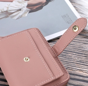 Close-up of pink leather wallet with litchi texture, metal zipper and snap button detail