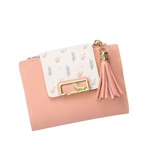 Detail of pink and beige leather wallet featuring leaf prints and a tassel pendant