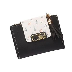 Close-up of short bifold wallet with black faux leather and leaf print flap with tassel