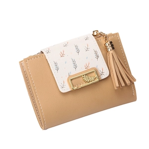 Detail of short leather wallet with leaf charm, tassel, and contrast flap detail