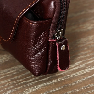 Detail of dark burgundy lychee leather waist bag with yellow stitching and metal zipper